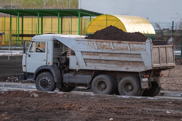 Camion à benne blanche avec de la terre dans la carrosserie arrière