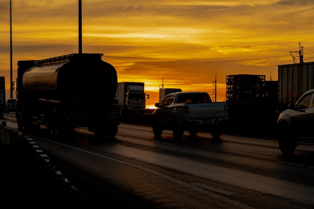 Camion avec cargaison roulant sur l'autoroute de transport routier au coucher du soleil en été