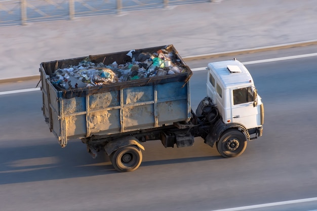 Photo un camion avec un conteneur métallique rempli d'ordures descend l'autoroute jusqu'à la décharge.