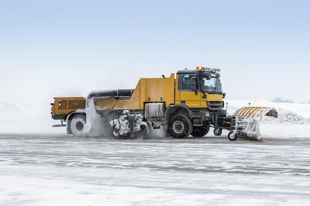 Un camion de déneigement nettoie le tablier de l'aéroport dans un blizzard