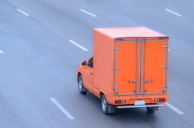 Camion orange fonctionnant sur la route, petit camion sur la route.