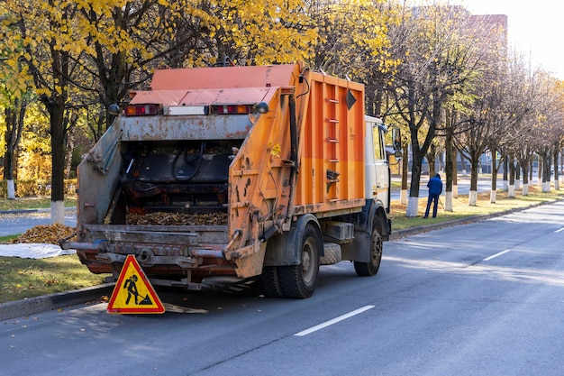 Le camion à ordures enlève les feuilles mortes d'automne Collecte et élimination des feuilles mortes dans la ville