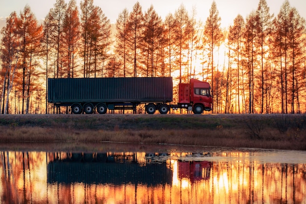 Camion rouge sur une route au coucher du soleil. Focus sur le conteneur