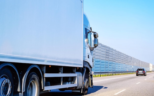 Camion en route d'été de Pologne. Camionneur sur autoroute. Camion effectuant des travaux de logistique. Semi remorque avec chauffeur. Grand lecteur de voiture de fret. Livraison de fret. Industrie des transports à l'exportation. Conteneur avec des marchandises