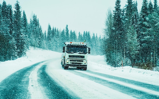 Camion sur la route d'hiver de neige de la Finlande. Camionneur sur autoroute. Camion effectuant des travaux de logistique. Semi remorque avec chauffeur. Grand lecteur de voiture de fret. Livraison de fret. Industrie des transports à l'exportation. Conteneur avec des marchandises