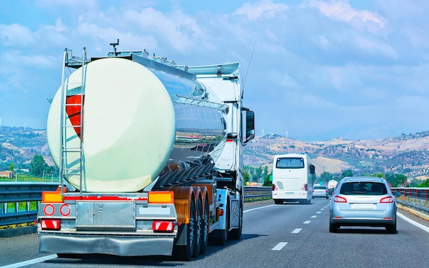 Camion avec stockage de liquide ou d'huile sur route ou autoroute d'Italie. Camion avec citerne de service-citerne au travail logistique. Citerne semi-remorque. Conduite de voiture de fret. Livraison de fret. Industrie des transports à l'exportation