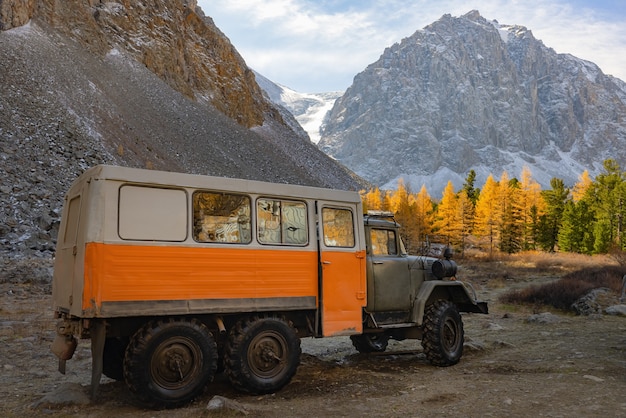 Le camion tout-terrain se dresse sur fond de mélèzes jaunes des montagnes