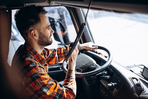 Camionneur homme conduisant dans une cabine de son camion et parlant sur un émetteur radio