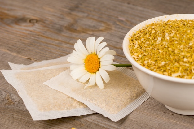 Camomille séchée et sachets de thé sur table en bois rustique