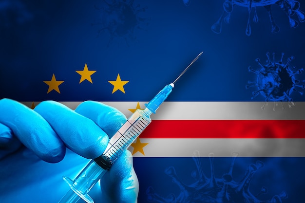 Campagne de vaccination du Cabo Verde Covid19 La main dans un gant en caoutchouc bleu tient une seringue devant le drapeau