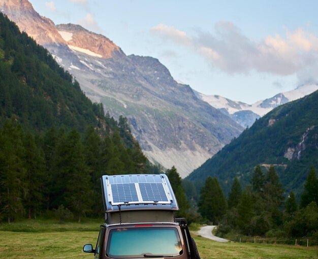 Camping-car avec un mini module solaire sur le toit debout sur un pré vert dans les Alpes suisses