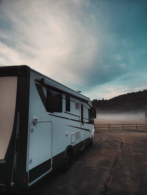 Camping-car de véhicule de camping-car garé dans la nature avec du brouillard et un beau ciel bleu en arrière-plan. Concept de gens de voyage et de vacances d'aventure