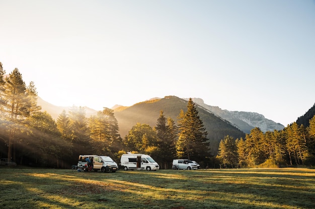 Camping-cars dans une vallée avec une vue imprenable sur les montagnes forestières et les rayons du soleil au lever du soleil