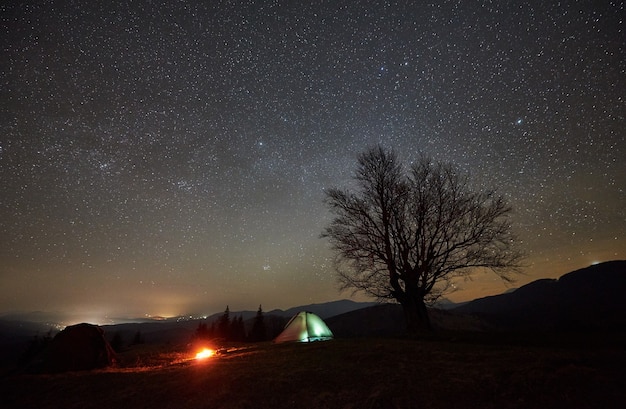 Camping de nuit dans la vallée de montagne sous un ciel étoilé