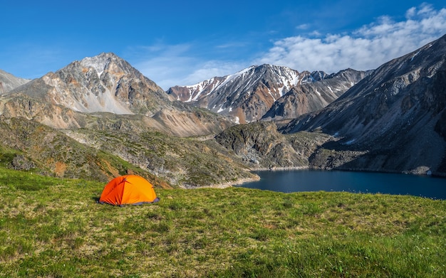 Camping sur un plateau verdoyant d'altitude en été. Vue panoramique sur un lac de montagne bleu dans l'Altaï avec tente sur le rivage. Beau lac turquoise.