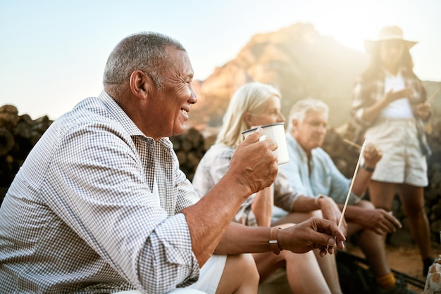 Camping senior détendu avec des amis prenant une pause et buvant une tasse de café tout en profitant de la retraite en gardant la santé à l'extérieur dans la nature Homme retraité souriant lors d'une retraite de bien-être