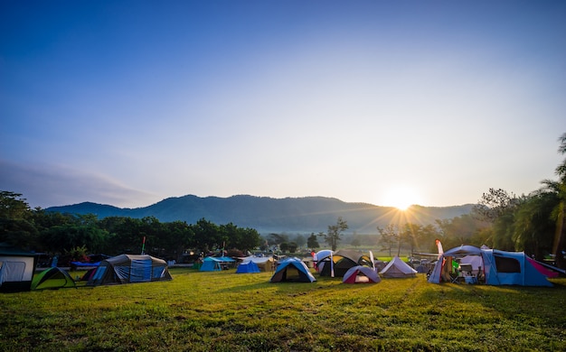 Camping et tente dans un parc naturel avec lever de soleil derrière la montagne