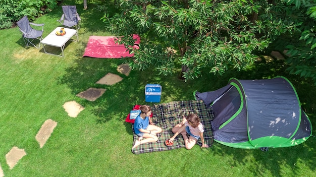 Camping vue aérienne d'en haut, mère et fille s'amusant, tente et équipement de camping sous l'arbre, vacances en famille au camp en plein air concept