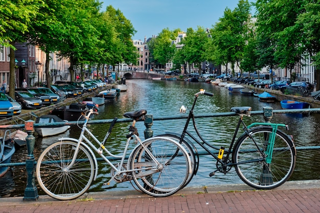Canal d'Amsterdam avec des bateaux et des vélos sur un pont