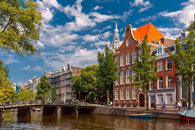 Photo canal d'amsterdam, pont, église et maisons typiques dans la journée d'été ensoleillée, hollande, pays-bas.