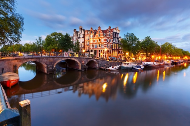 Canal d'Amsterdam, pont et maisons typiques, bateaux et vélos pendant l'heure bleue du crépuscule du soir, Hollande, Pays-Bas. Tonifiant utilisé