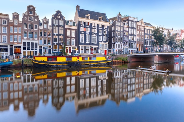 Canal d'Amsterdam Singel avec maisons hollandaises typiques, pont et péniches pendant l'heure bleue du matin, Hollande, Pays-Bas.