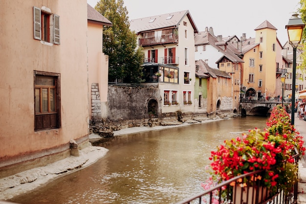 Canal d'eau de la ville d'Annecy avec fleurs rouges et bâtiments anciens. Photo de haute qualité