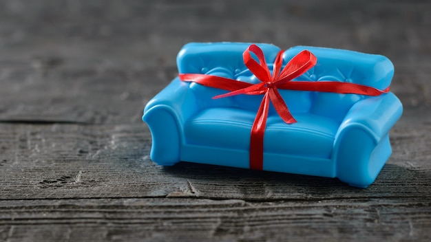 Canapé bleu jouet, décoré comme cadeau sur une table en bois.