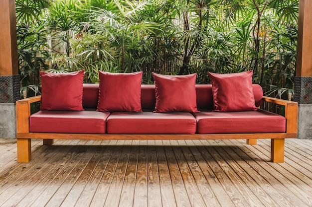 Canapé en bois avec coussin rouge sur plancher en bois dans le jardin.