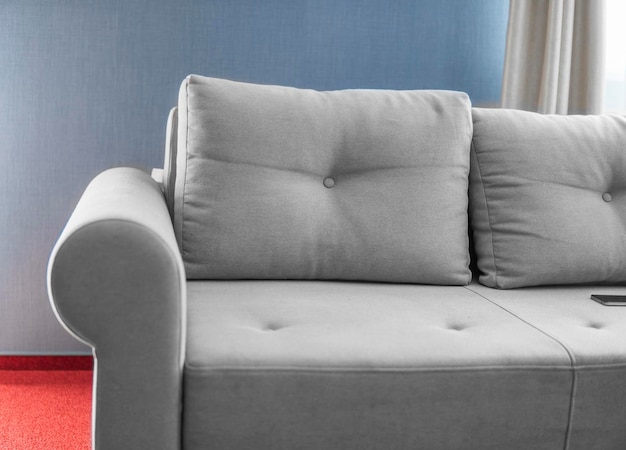 Canapé gris confortable dans un salon avec mur bleu et sol rouge