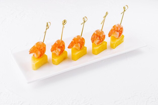 Canapés avec des crevettes et de l'ananas sur une assiette