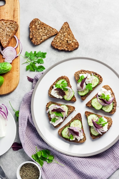 Canapés avec pain grillé au tournesol et graines de lin feta concombre et oignon