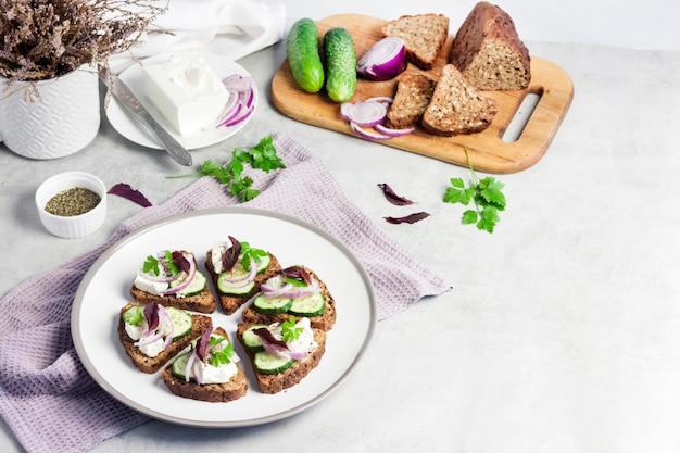 Canapés avec pain grillé aux graines de tournesol et de lin, fromage feta, concombre et oignon