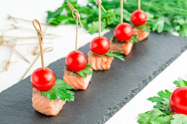 Canapés avec truite frite, tomates cerises et persil. Sur une ardoise sombre. Fermer. Isolé. fond blanc