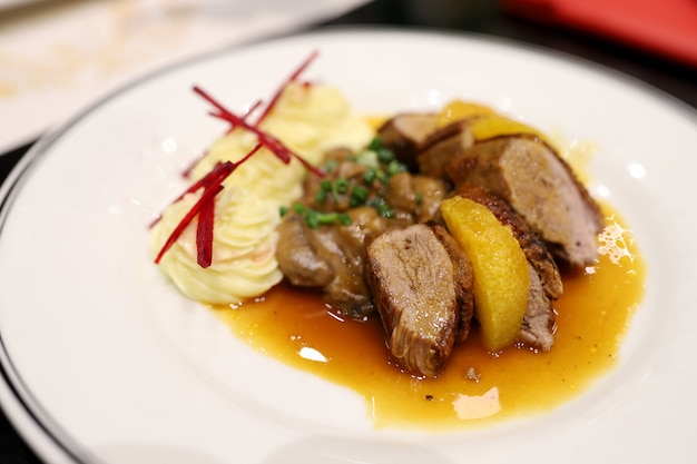 Canard rôti garni de sauce à l'orange et de purée de pommes de terre Décorez le plat appétissant sur l'assiette blanche du restaurant.