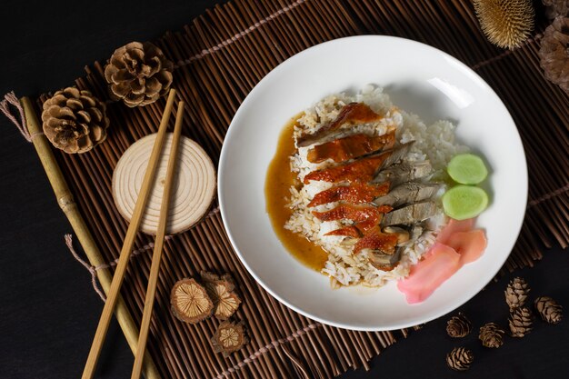 Canard rôti sur riz avec baguettes en plaque blanche, cuisine de rue thaïlandaise.