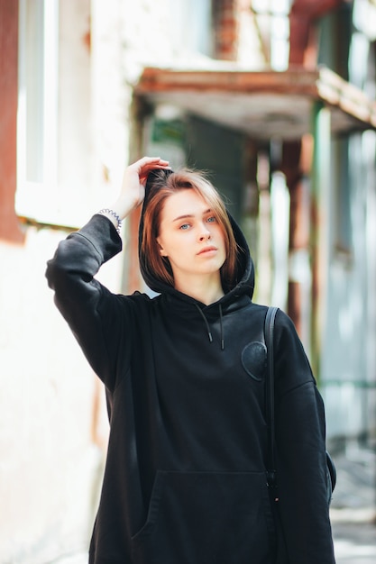 Candid portrait de hipster de mannequin fille beaux cheveux longs jeune en Sweat à capuche noir sur la ville