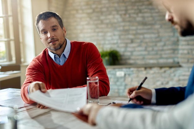 Candidat masculin ayant un entretien d'embauche et donnant son CV à un membre de l'équipe des ressources humaines du bureau