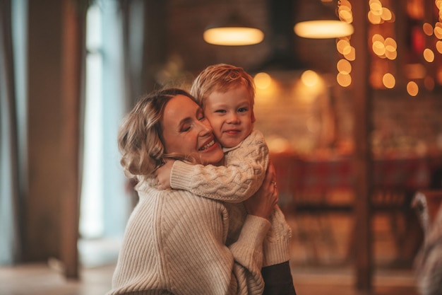 Candide authentique maman heureuse passe du temps avec son enfant joyeux au pavillon en bois décoré de Noël