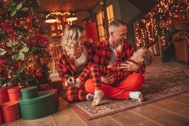 Candide authentique mignonne famille heureuse en pyjama à carreaux rouges passe du temps ensemble au lodge décoré de Noël