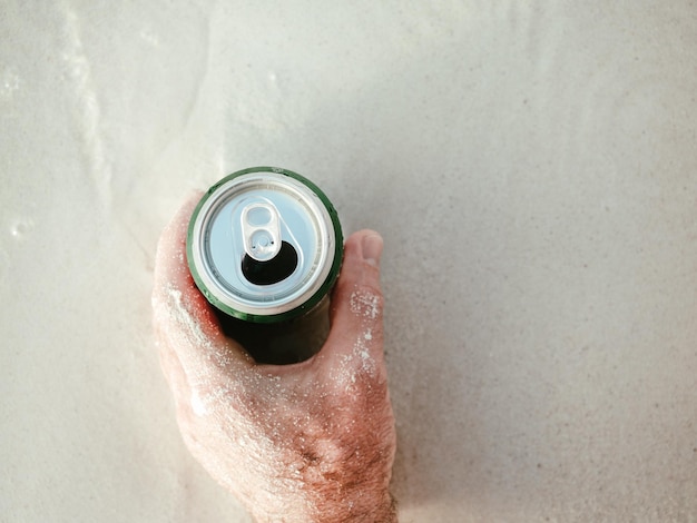 Canette de bière et un homme séduisant sur le fond de la piscine. Vue de dessus, gros plan. Concept de vacances et de voyage. Moments de fête