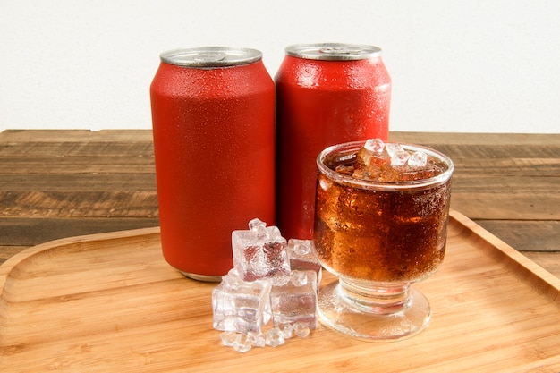 Canette de soda avec un verre plein de glace et boire sur un plateau en bambou