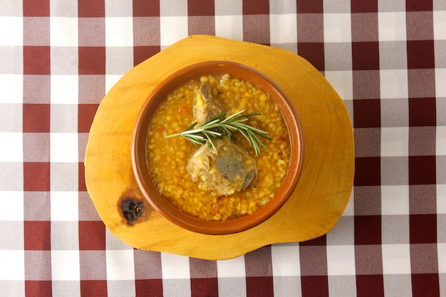 Canjiquinha un plat traditionnel de la cuisine brésilienne à base de côtes de porc et de maïs écrasé, dans un bol en céramique sur une table en bois rustique. Vue rapprochée