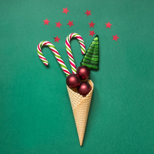 Canne de Noël, boules rouges dans le cornet de crème glacée sur vert.