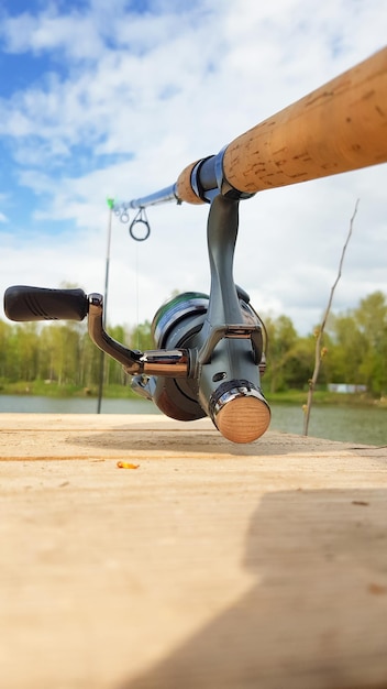 Canne à pêche à la carpe isolée sur le lac et pont en bois. Moulinet de filature d'alimentation de carpe se bouchent. Pêche à la carpe sur le lac. L'équipement du pêcheur. Photographie verticale.