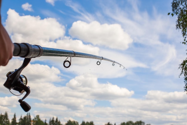 Canne à pêche sur un fond de ciel bleu dans la main d'un homme