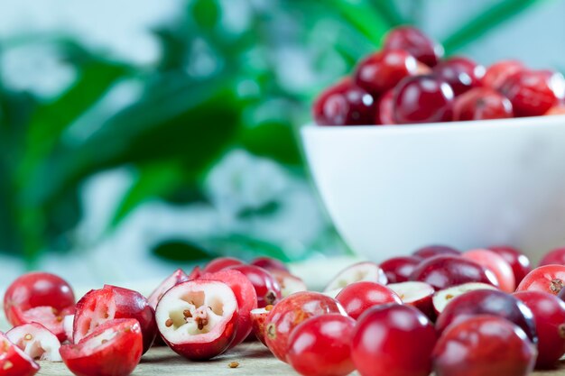 Canneberges maison cultivées dans un jardin industriel coupées en tranches, canneberges utiles coupées rouges, canneberges rouges divisées mûres sur la table