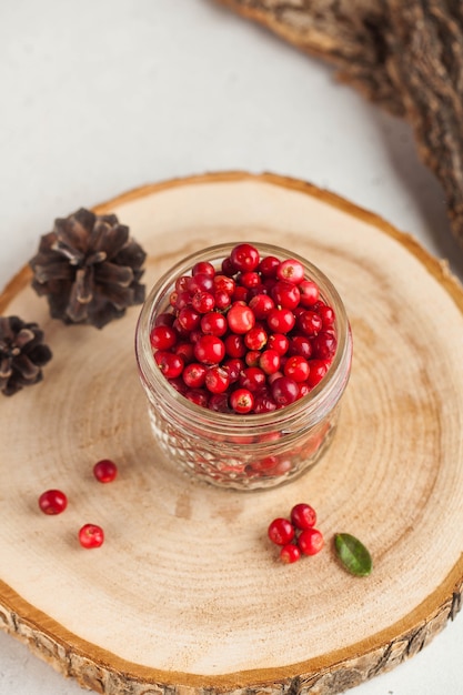 Canneberges mûres fraîches dans un bocal en verre transparent sur un support en bois. L'automne, baies utiles. Récolte..