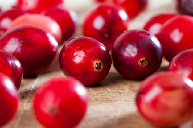 Canneberges rouges entières mûres sur la table, canneberges faites maison cultivées dans un jardin industriel, canneberges saines aigres rouges entières