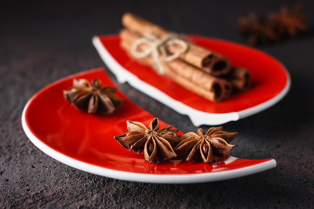 Cannelle et anis sur une assiette fendue rouge.